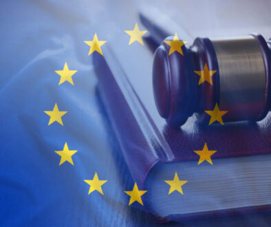 A judge’s gavel rests on a thick law book. The image is overlaid with the European Union flag, featuring a circle of twelve yellow stars on a blue background, symbolizing European law or justice.